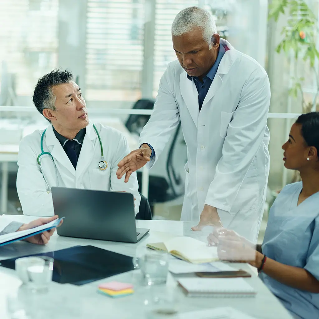 Group of doctors gathered around a computer working in partnership