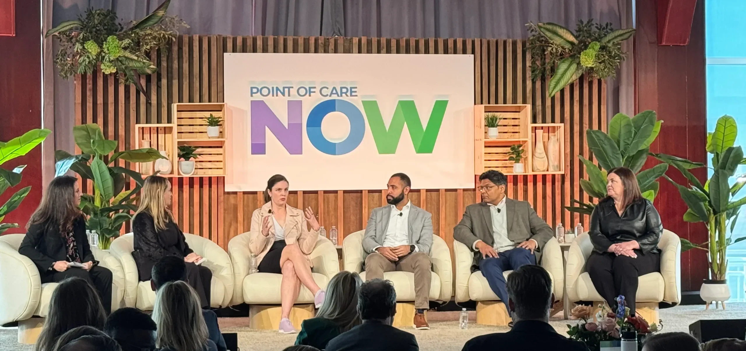 Panel discussion on stage at the POC Now Summit 2025, with 6 people on stage 