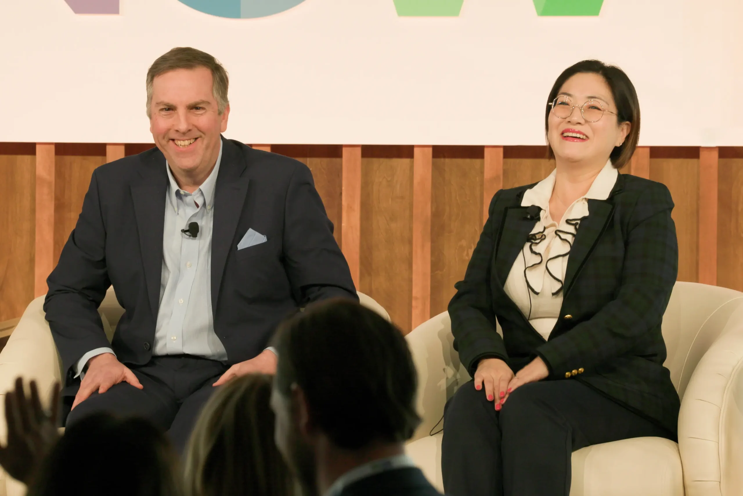 Two people on stage at the POC Now Summit 2025, laughing together 