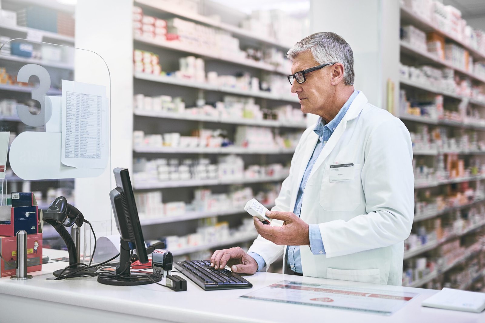 Pharmacist working at pharmacy front desk computer
